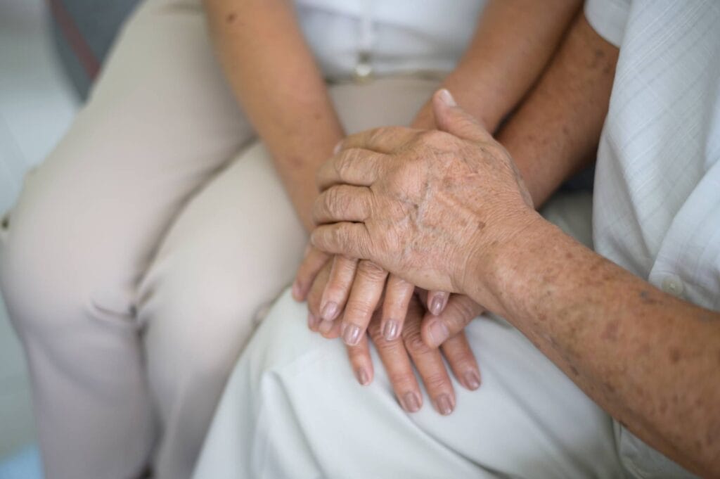 Pflegekraft hält die Hand eines älteren Menschen zur Unterstützung.